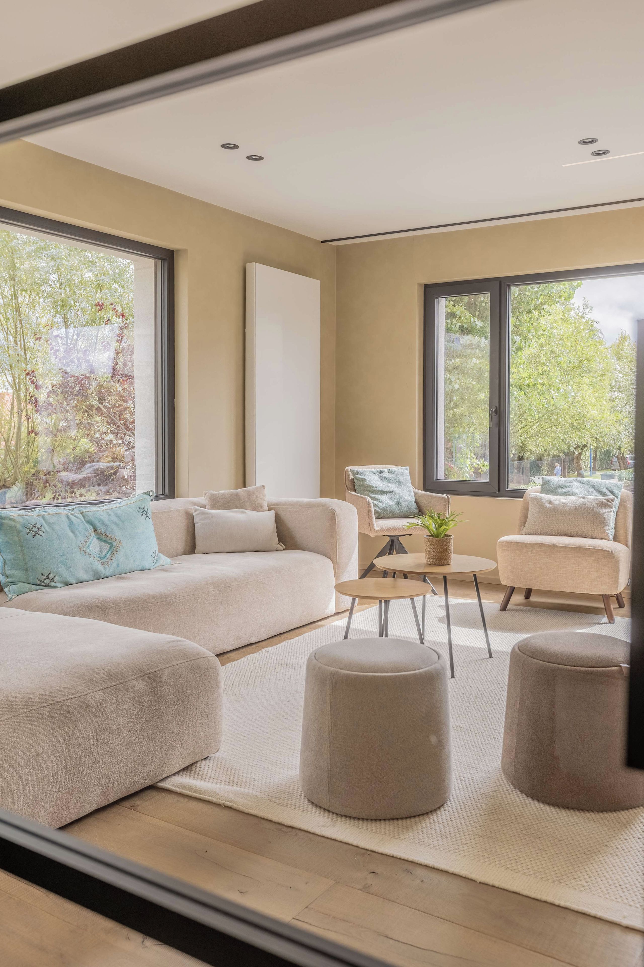Een moderne woonkamer met een hoekbank, een klein rond tafeltje en een stoel.