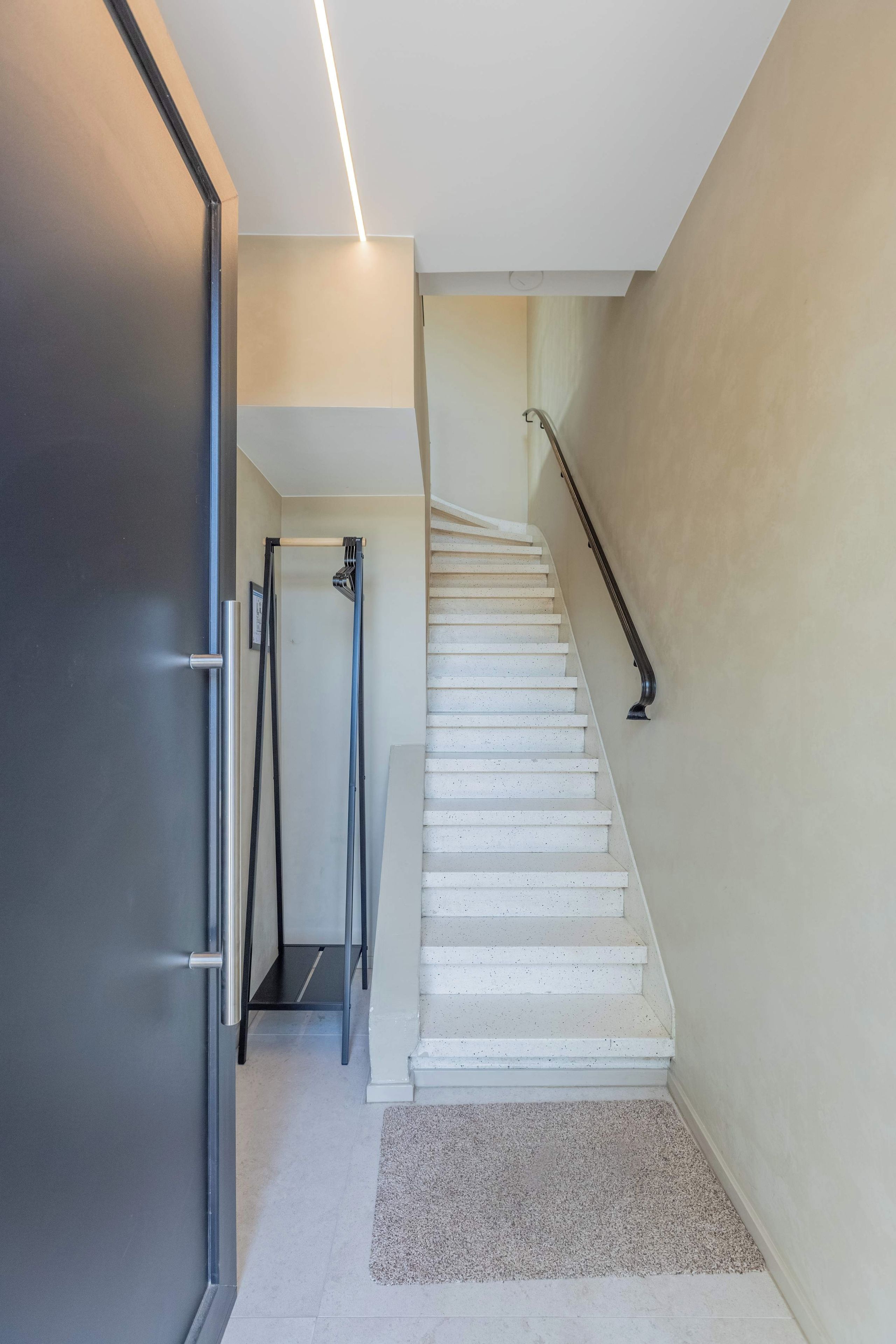 A staircase with white steps and a handrail, leading to an upper floor.