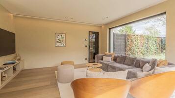 Ein modernes Wohnzimmer mit einem Ecksofa, einem Couchtisch und einem Fernseher.