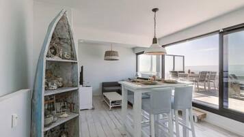 A modern interior with a dining area, a white shelf unit, and a large window overlooking a balcony.