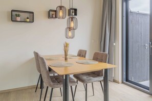 Un espace repas comprenant une table en bois, six chaises et trois lampes suspendues.