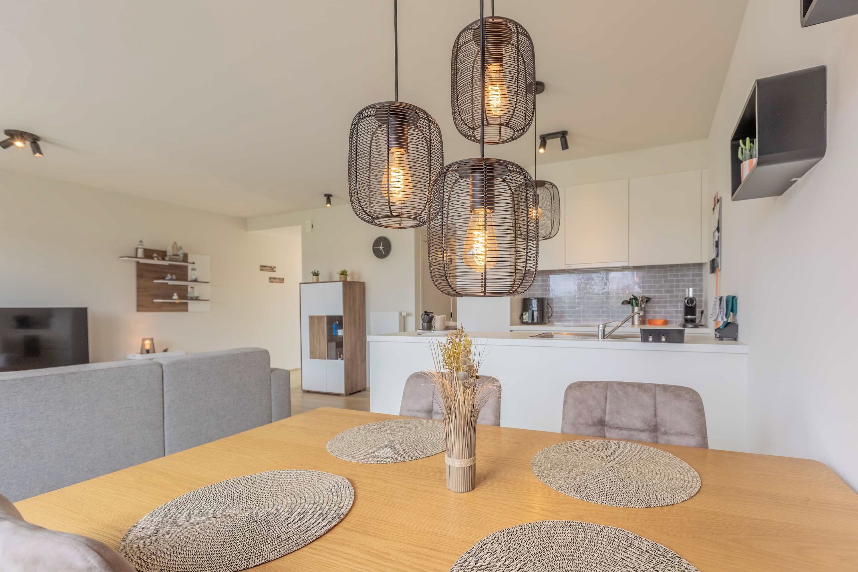 A modern kitchen with white cabinets, a built-in oven, and a coffee machine.
