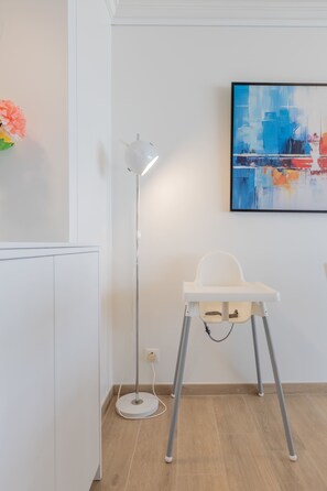 Una camera moderna con un lampadario da terra bianco, una sedia bianca e un quadro appeso al muro.