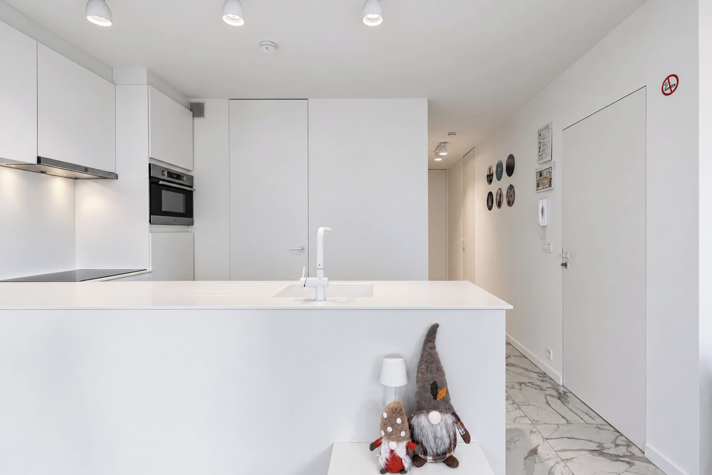 A modern kitchen with white cabinetry, a built-in oven, and a white countertop.