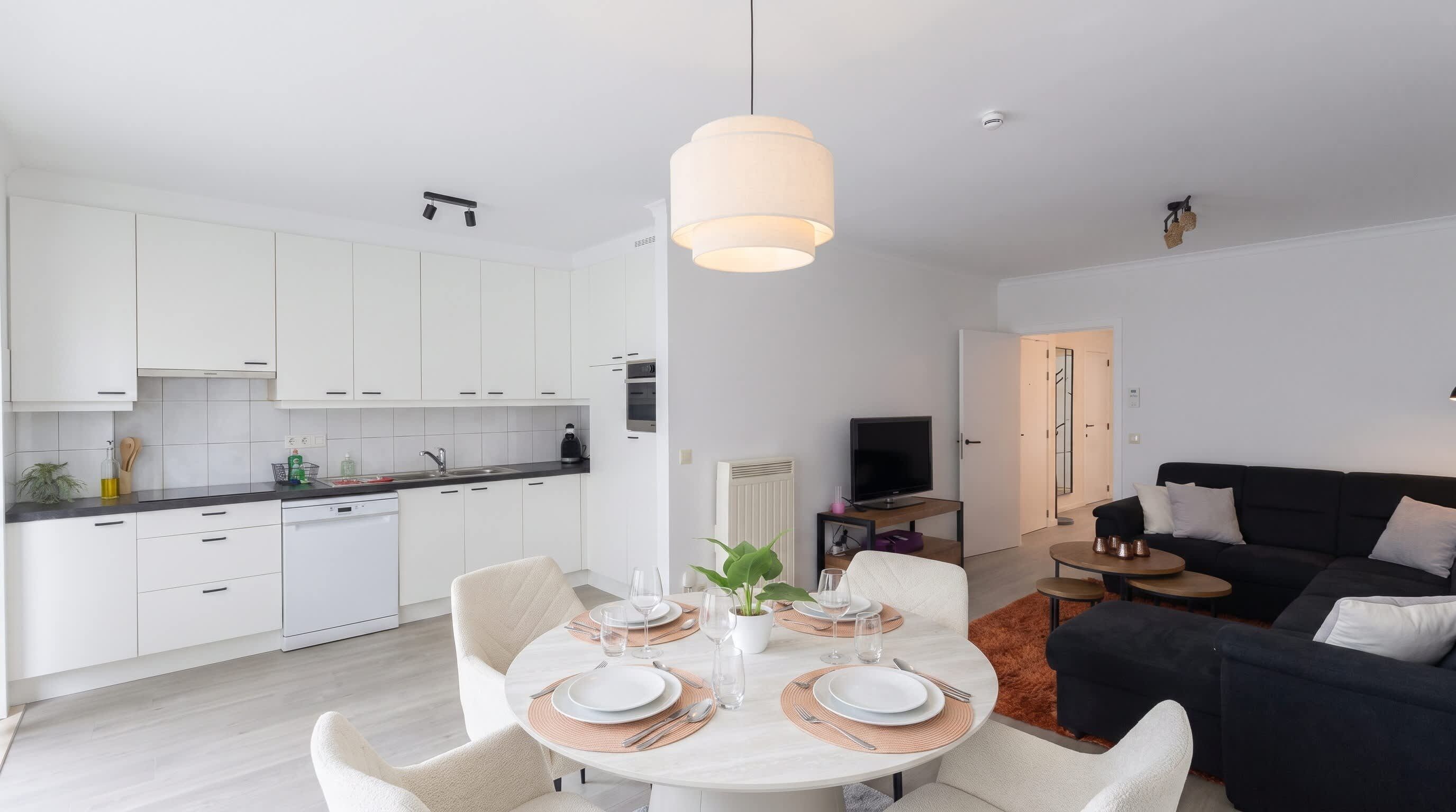 A modern apartment with a dining area, kitchen, and living space.