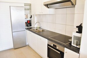 Eine moderne Küche mit weißen Schränken, einem Edelstahl-Kühlschrank, einem Einbauofen und einer Mikrowelle.
