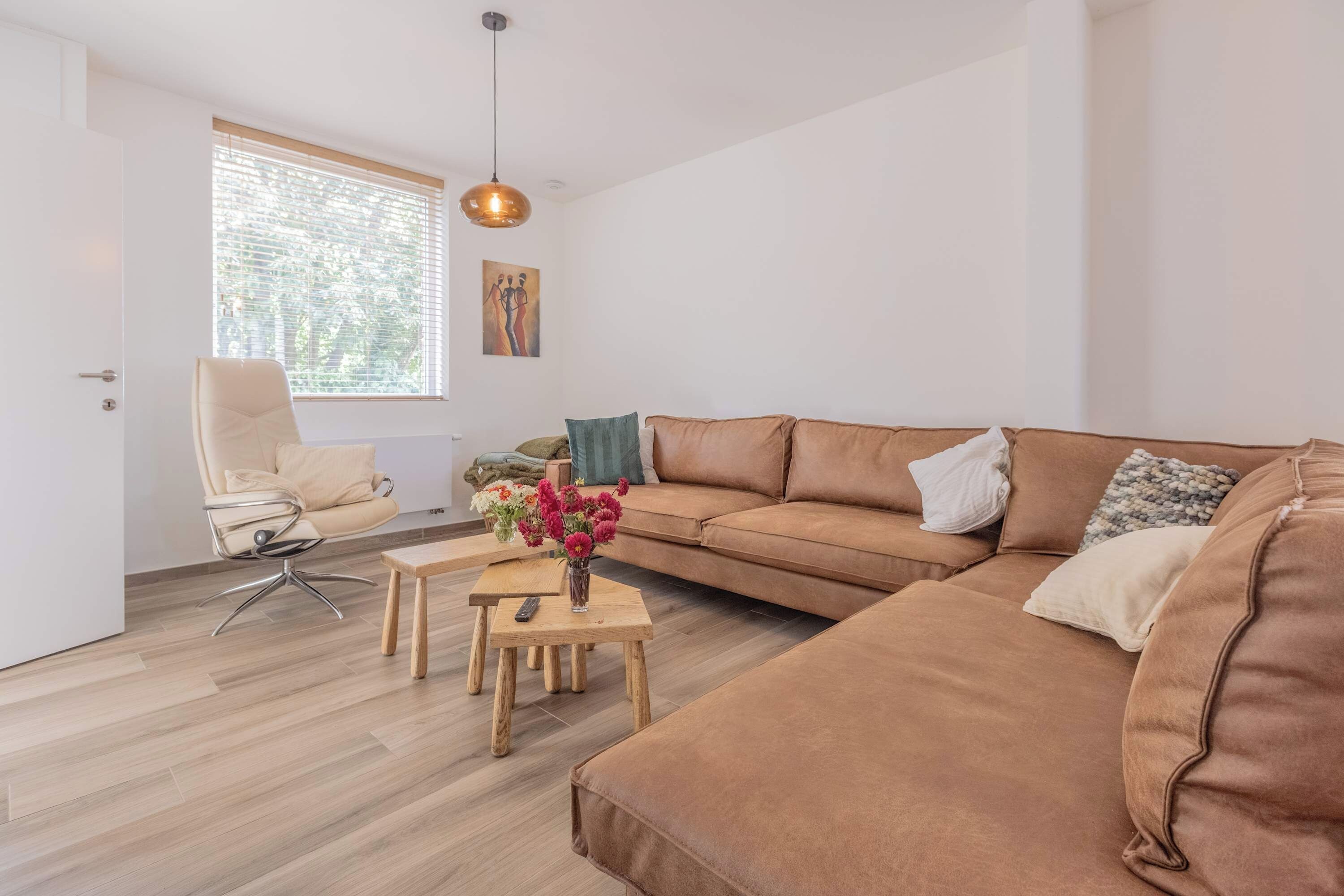 A modern living room with a sofa, a chair, a coffee table, and a hanging light fixture.
