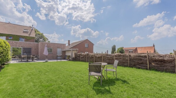 Ein Wohnhaus mit gepflegtem Rasen, Sitzgelegenheit im Freien und einer Ziegelhausfassade.