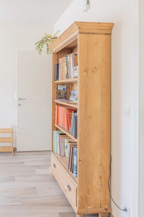 Een houten boekenkast met boeken en een kleine plant erop.