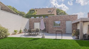 Eine Terrasse mit einer Ziegelwand, einem Tisch mit Stühlen und einem Blumentopf.
