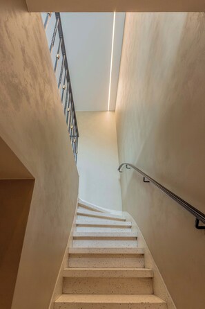 A staircase with a handrail, leading upwards to a landing with a skylight. - Villa Hélène · bright upstairs flat, 3 bedrooms (Koksijde)