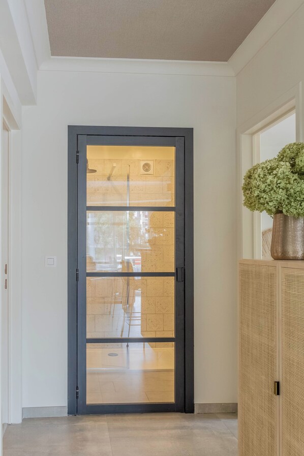 A modern interior with a dark-framed glass door, a potted plant, and a textured wall panel. - Marée de la mer · 1 minute from the beach (Ostend)