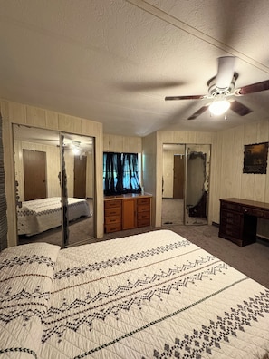 A bedroom with a bed, a dresser, a desk, and a ceiling fan. - Cozy 2-bedroom mobile home in adorable Chouteau with AC (Chouteau)