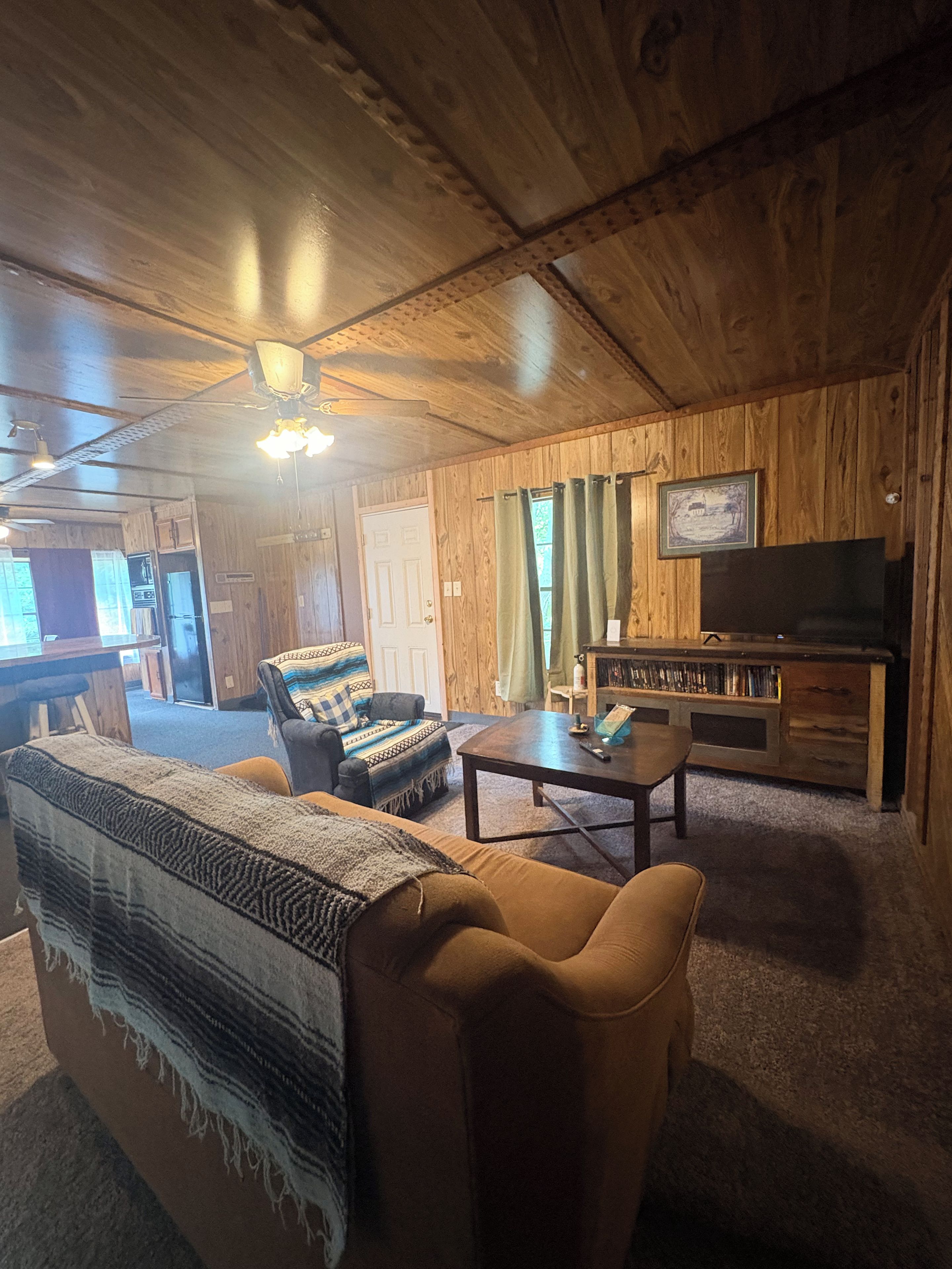 A cozy living room with wooden walls, a sofa, a coffee table, and a television.