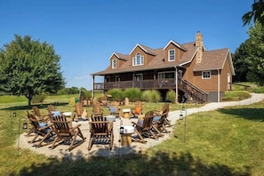 A large house with a porch, outdoor seating area, and a chimney.