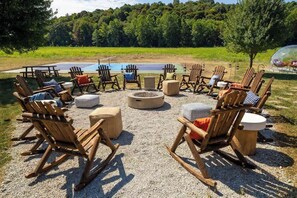 Un espacio al aire libre con sillas de madera y un pozo de fuego.