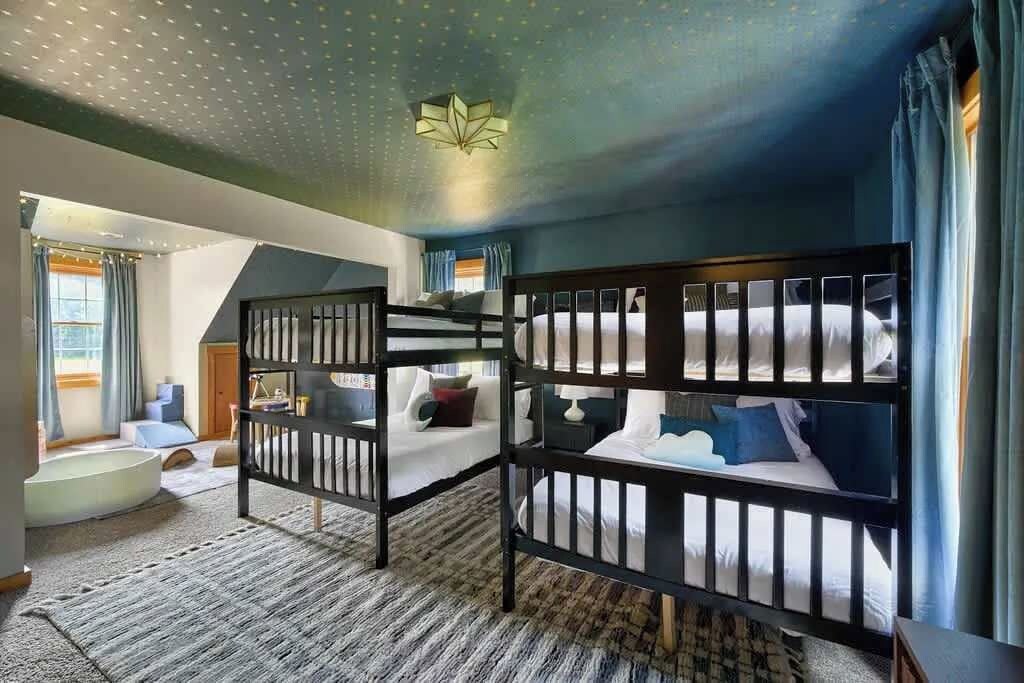Une chambre avec des lits superposés, une baignoire et un luminaire fixé au plafond.
