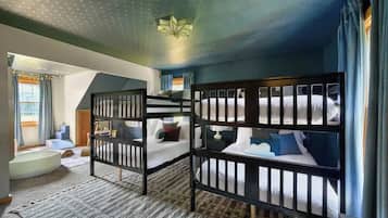 Une chambre avec des lits superposés, une baignoire et un luminaire fixé au plafond.