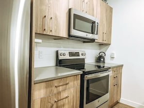 Une cuisine avec des meubles de rangement en bois, un four à micro-ondes, une cuisinière et un four traditionnel.