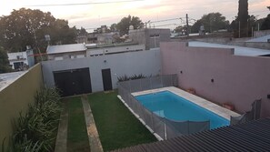 Zona residencial con piscina, césped pequeño y edificio de techo plano.