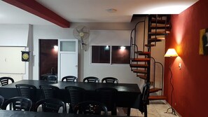 Un comedor con una mesa y sillas, un ventilador, una ventana y una escalera.