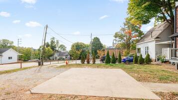 Un barrio residencial con entrada pavimentada, una casa con porche y un patio cercado.