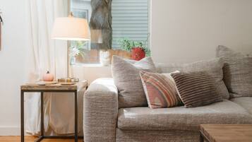 A living room with a sofa, a small table with a lamp, and a framed picture on the wall.