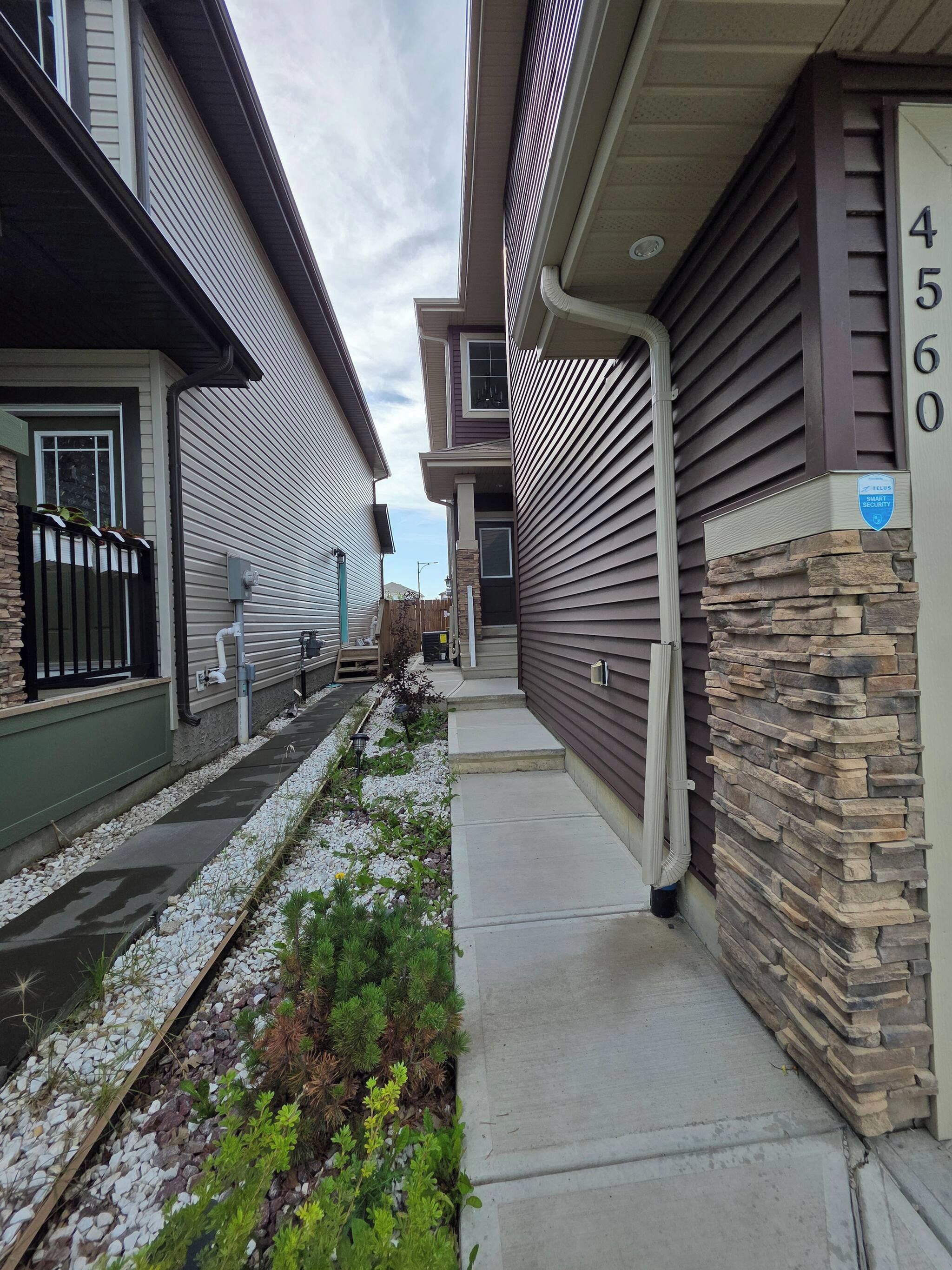 Una calle residencial con casas, un muro de piedra y una acera.