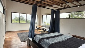 A bedroom with a bed, a desk, and large windows. - Arabian Horse Farm House · Ocean View · Monteverde · Adults Only (Monteverde)