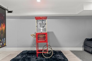 A vintage red vending machine labeled 'CONCESSIONS' in a room with gray walls, a black rug, and a black leather couch. - HYPE BEAST THEMED STR (Philadelphia)