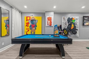 A pool table in a room with artwork on the walls, a mirror, and a framed picture. - HYPE BEAST THEMED STR (Philadelphia)