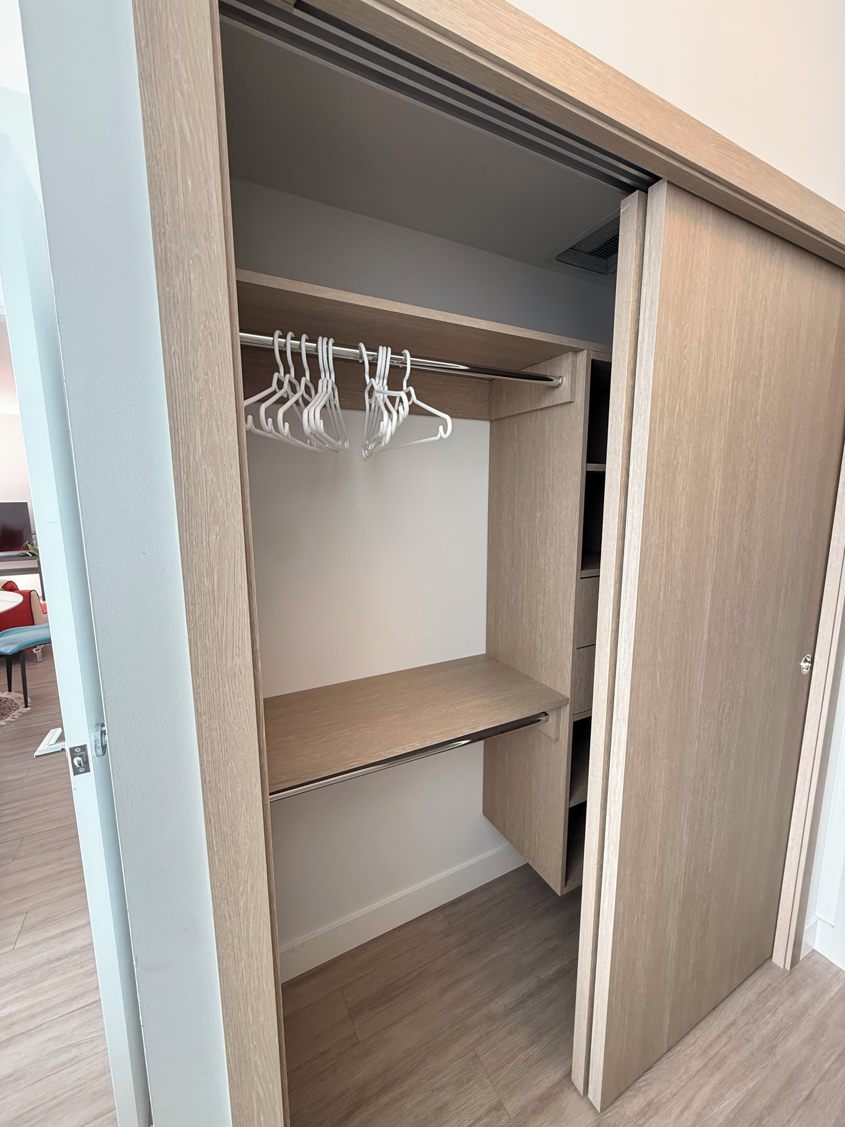 Een inloopkast met houten planken en een metalen kledingroede.