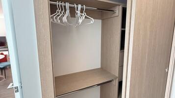 Een inloopkast met houten planken en een metalen kledingroede.
