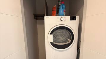 Een wasserette met twee gestapelde wasmachines en een rode schoonmaakfles erboven.