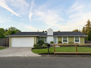 Ein eingeschossiges Haus mit Garage, eingezäunter Garten und blauem Himmel.