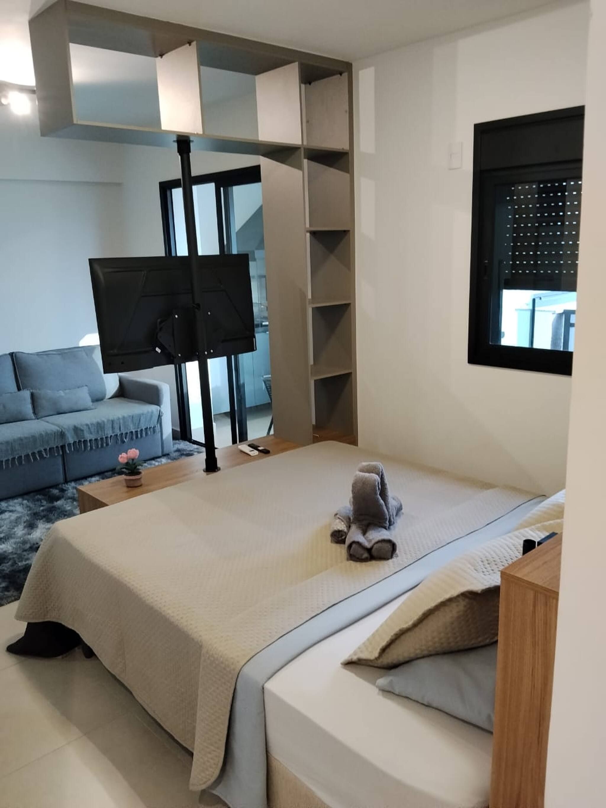 Un dormitorio con cama, sofá, televisión y ventana.