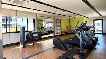 Un gimnasio con cintas de correr, una bicicleta estática y un banco de pesas.