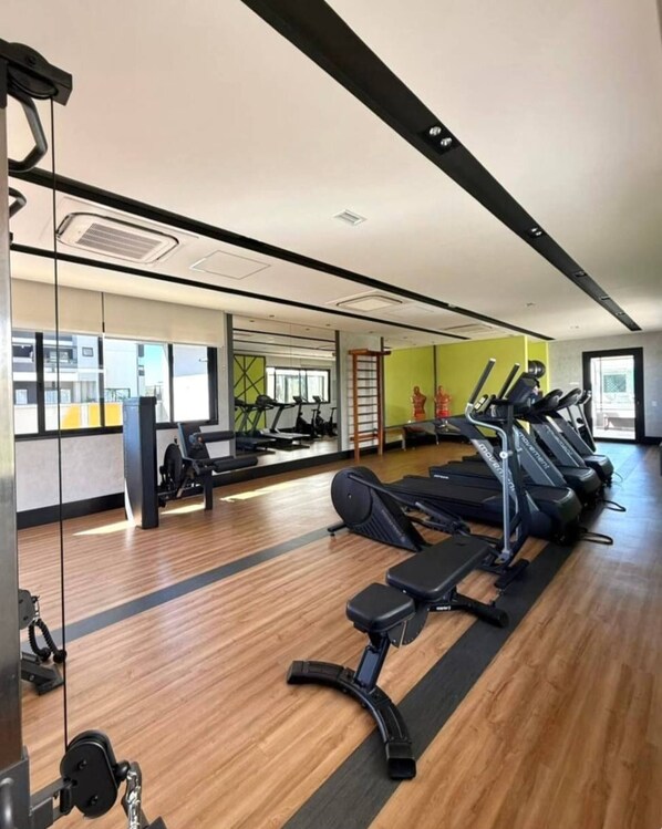 Une salle de sport équipée de tapis de course, d’un vélo d’appartement et d’un banc de musculation.