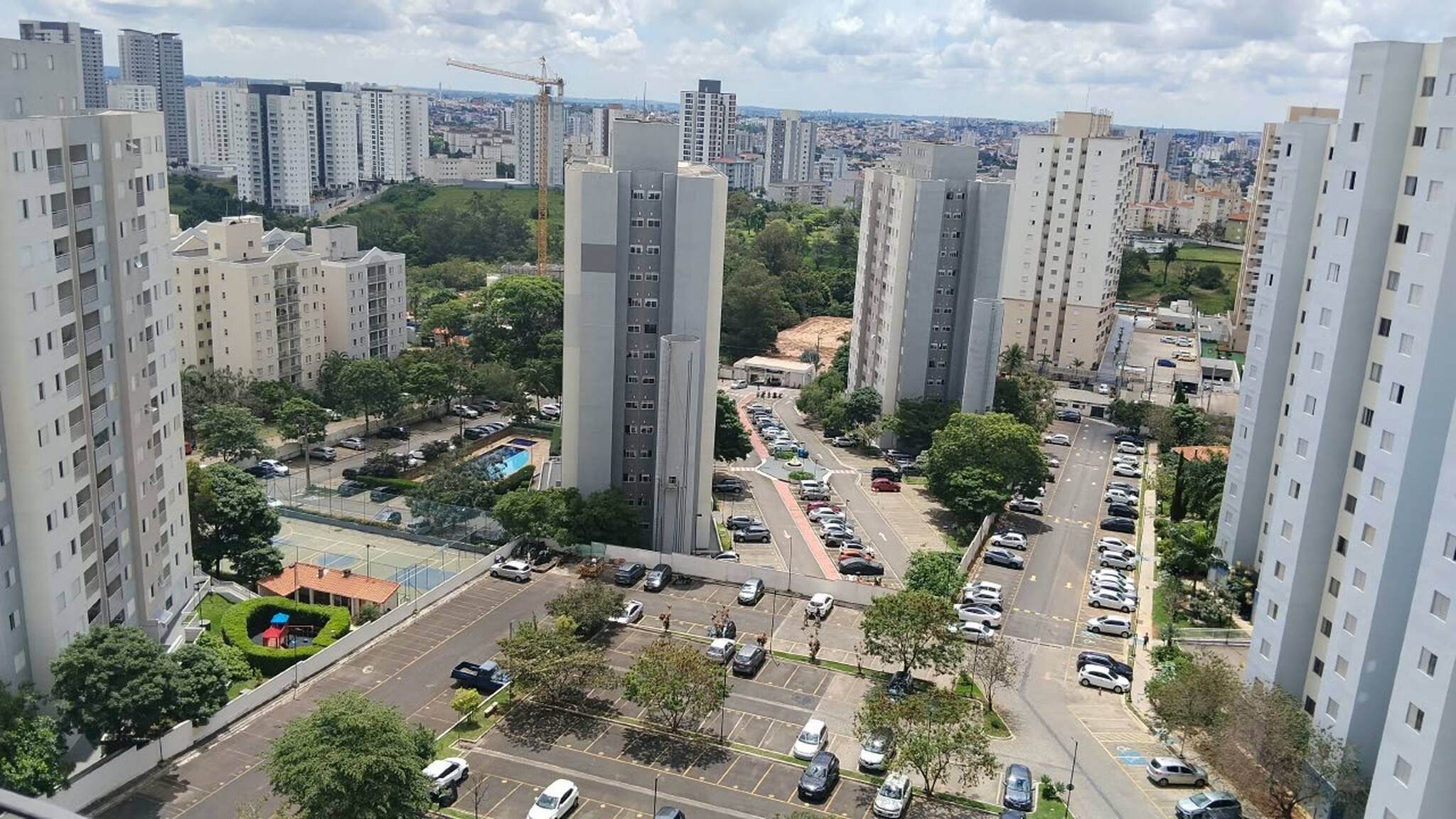 Zona residencial con edificios altos, un estacionamiento y una grúa de construcción a lo lejos.