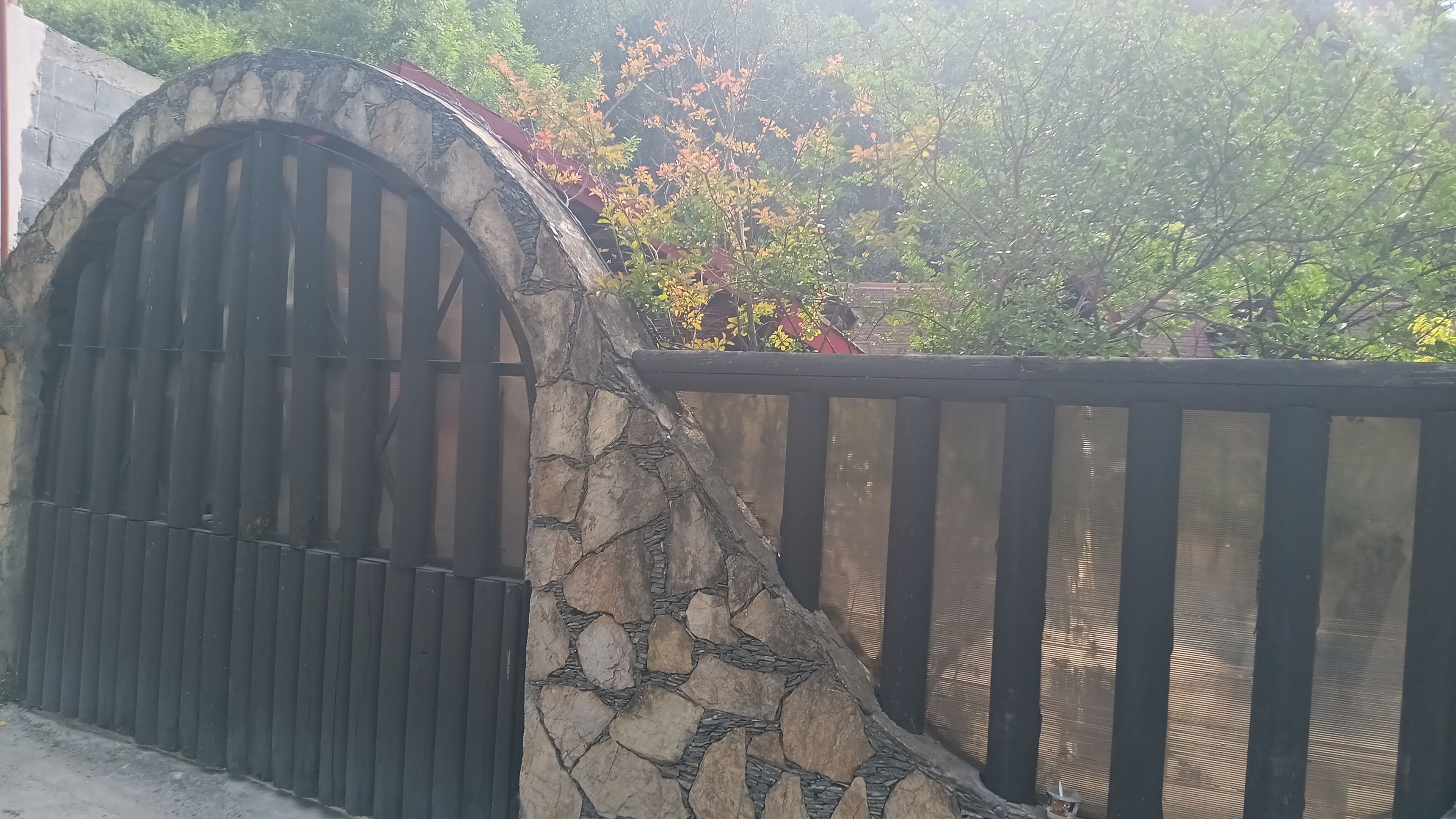 A gated entrance with a stone archway and a metal fence.