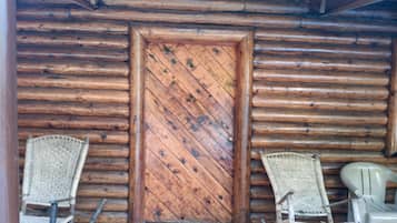 A wooden door with a diamond pattern, flanked by wicker chairs and a plastic chair.