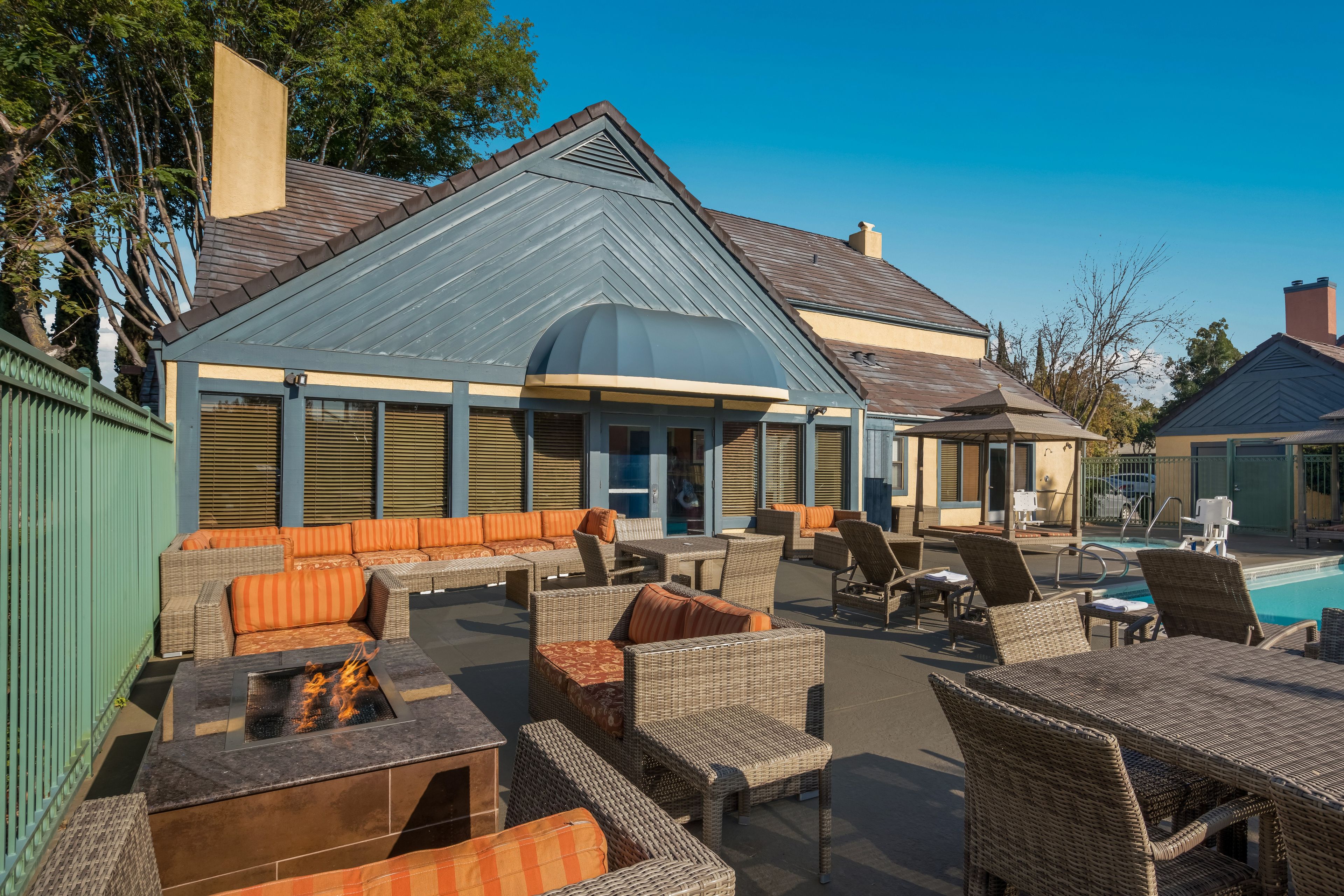 A poolside area with wicker furniture and a fire feature.