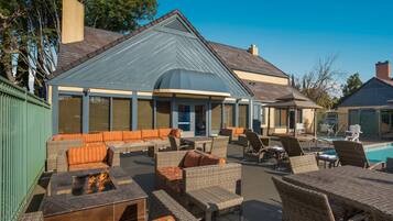 A poolside area with wicker furniture and a fire feature.