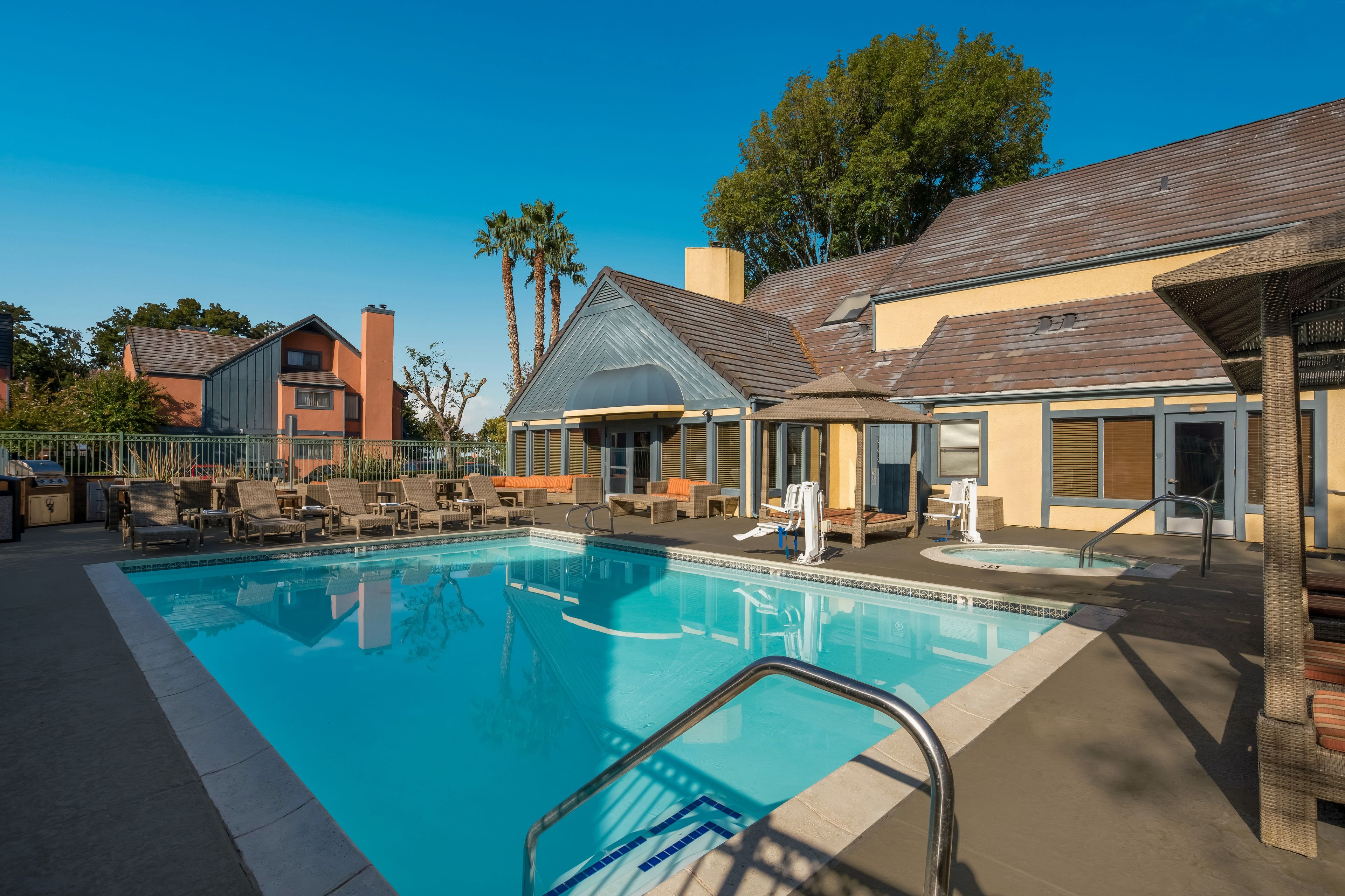 A swimming pool with lounge chairs and a covered seating area.