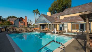 A swimming pool with lounge chairs and a covered seating area.
