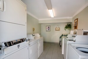 A laundry room with stacked washers and dryers, a telephone, and a picture on the wall. - Su Casa Suites (Livermore)