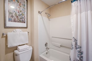 A bathroom with a toilet, a shower with a glass door, and a towel rack. - Su Casa Suites (Livermore)