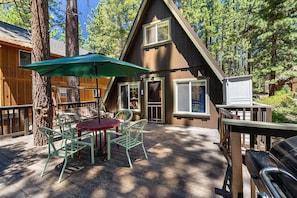 A wooden cabin with a deck, a table with chairs, and an umbrella.