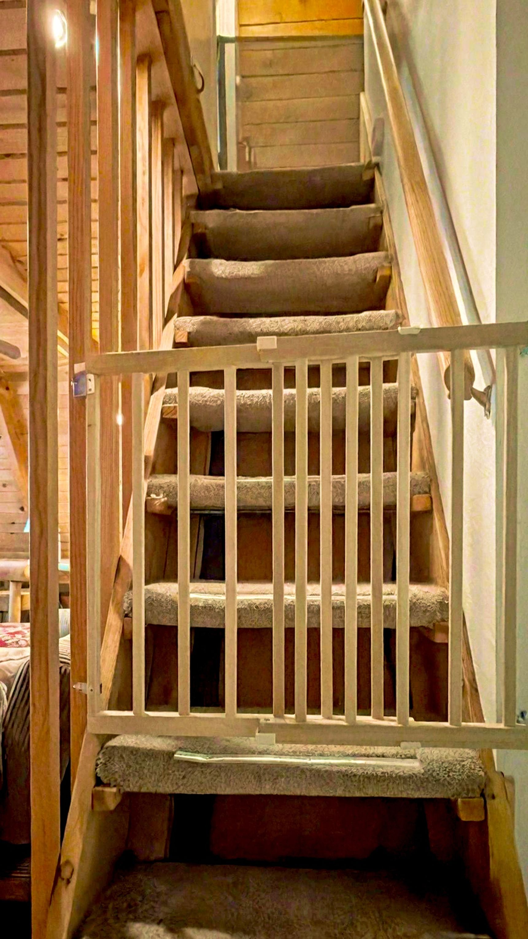 Een houten trap met een wit beveiligingspoortje.