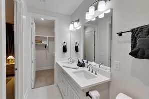 A modern bathroom with a double sink vanity, a large mirror, and a towel rack.